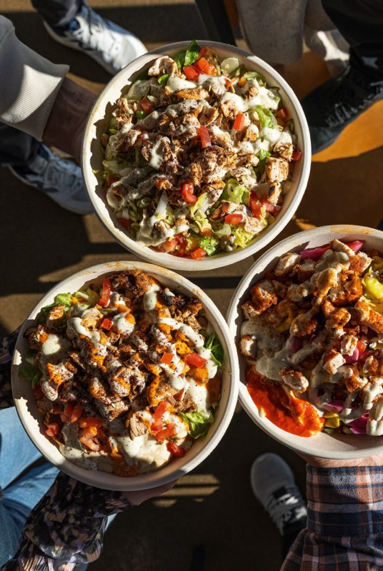 Three Hummus & Garlic bowls held up in the sunlight